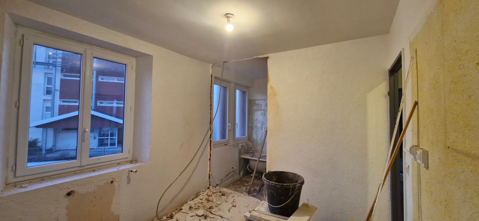 Pièce en cours de rénovation à Dax, avec murs partiellement déposés, gravats au sol et préparation des surfaces dans le cadre de la transformation d'un appartement en colocation de 4 chambres.