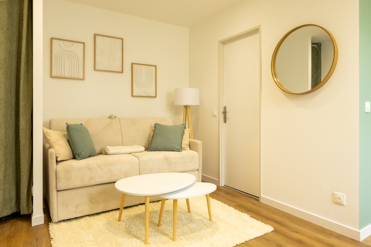 Salon aménagé avec canapé convertible et décoration contemporaine dans un appartement rénové à Dax