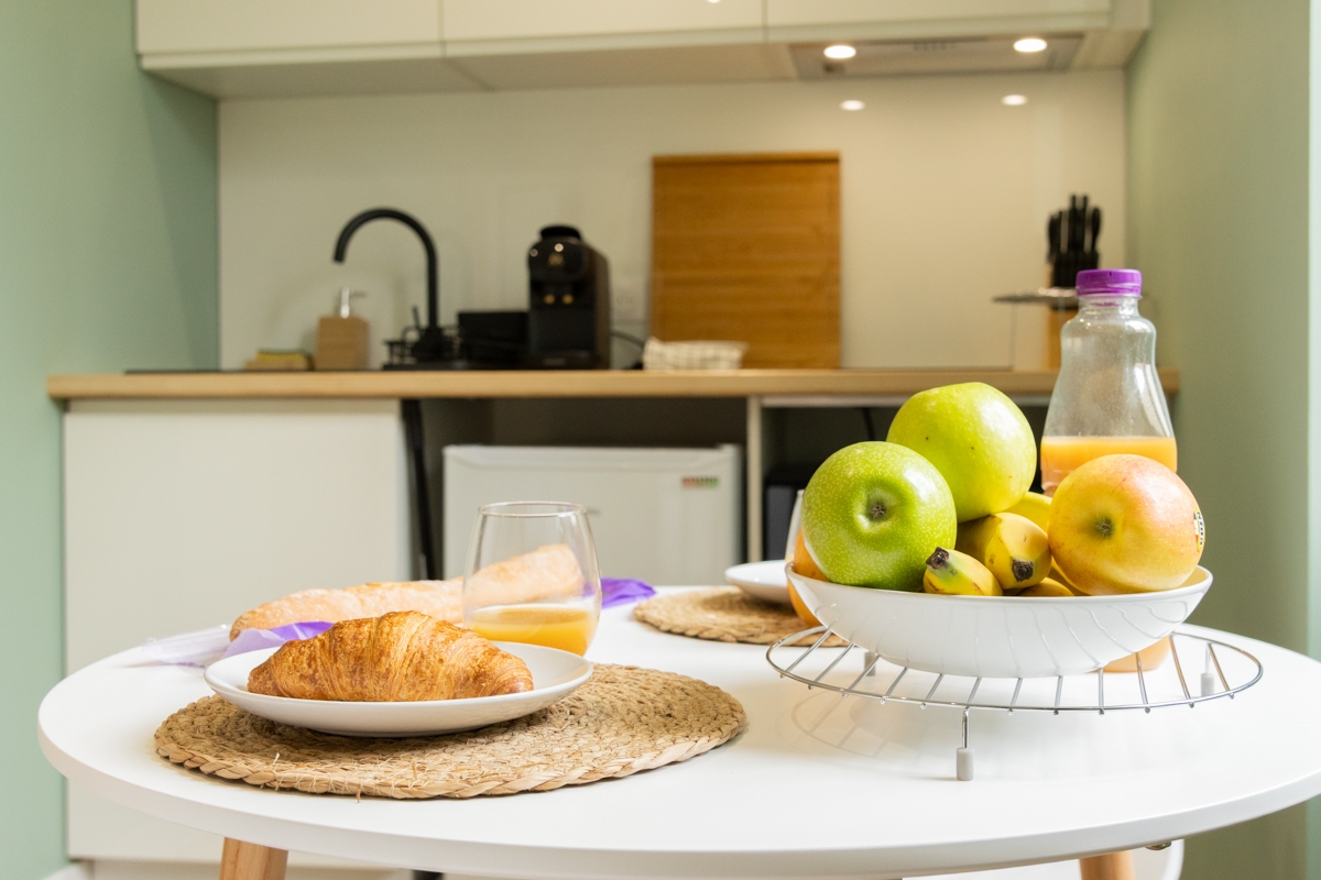Séjour avec cuisine ouverte et décoration vert sauge après rénovation complète à Dax