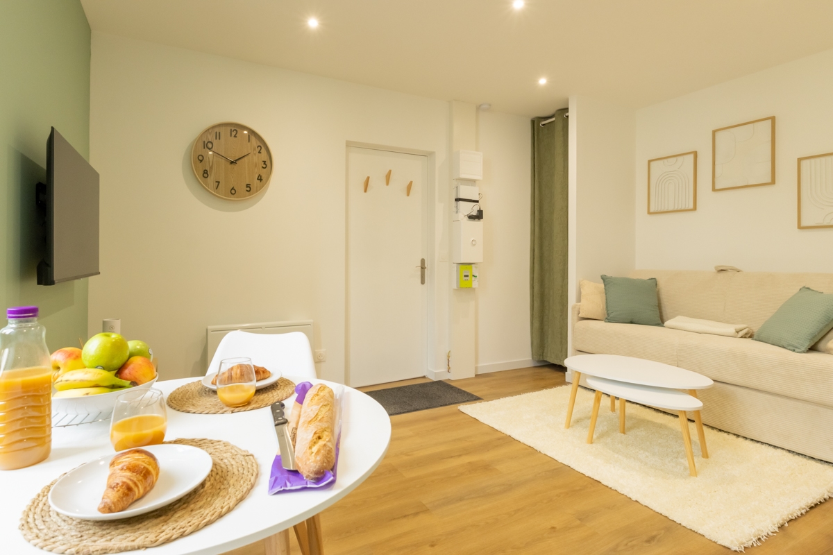 Séjour avec cuisine ouverte et décoration vert sauge après rénovation complète à Dax